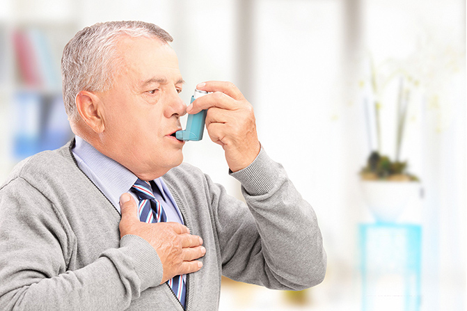 mature man treating asthma with inhaler at home